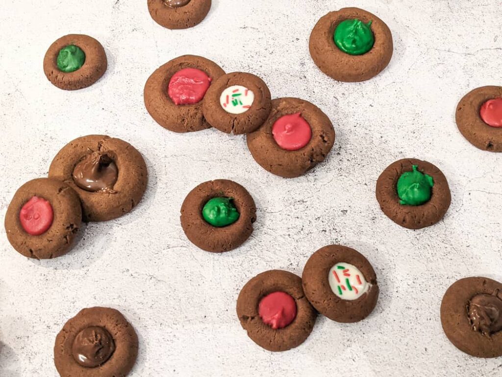 Chocolate thumbprint cookies filled with colored white chocolate and some with nutella, perfect for holiday christmas season